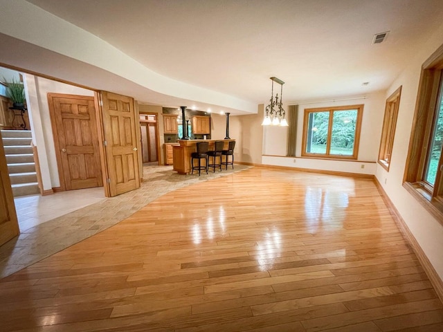 unfurnished dining area with light wood-type flooring and a notable chandelier