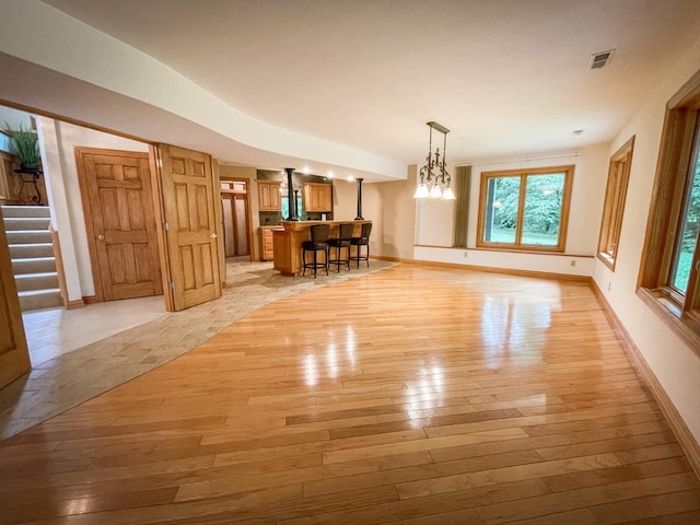 6643 E Turner Springs Dr, Springfield, MO 65809 - dining room featuring baseboards, light wood-style flooring, stairs, visible vents, and indoor bar