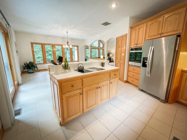 kitchen with appliances with stainless steel finishes, a chandelier, light tile patterned floors, decorative light fixtures, and a kitchen island