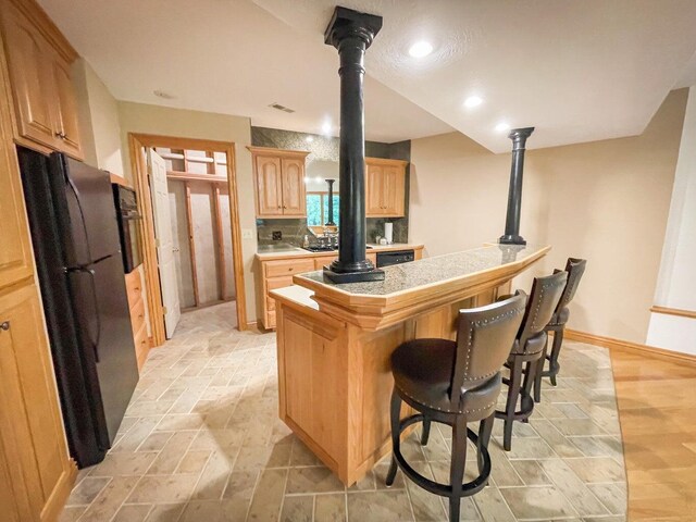 6643 E Turner Springs Dr, Springfield, MO 65809 - kitchen featuring visible vents, stone tile flooring, light countertops, a kitchen breakfast bar, and black appliances