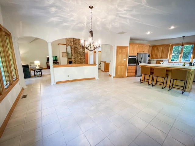 6643 E Turner Springs Dr, Springfield, MO 65809 - kitchen with arched walkways, an inviting chandelier, a breakfast bar, appliances with stainless steel finishes, and decorative columns
