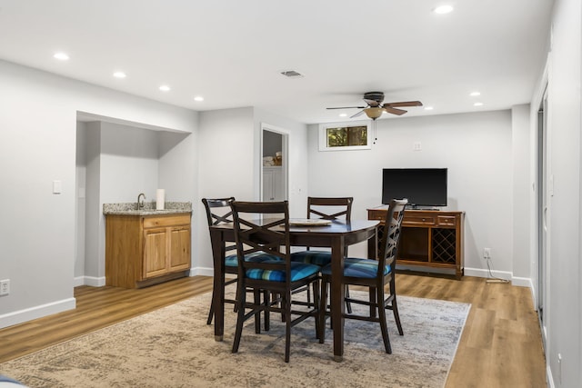 dining room featuring ceiling fan, indoor wet bar, and light hardwood / wood-style floors