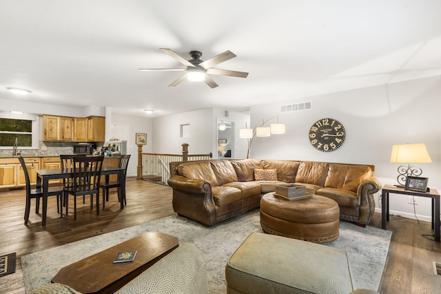 living room with hardwood / wood-style flooring, ceiling fan, and sink