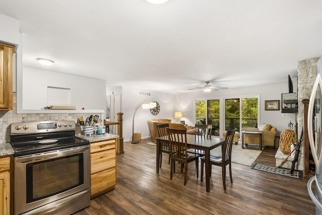 kitchen with dark wood-type flooring, appliances with stainless steel finishes, light stone countertops, and decorative backsplash