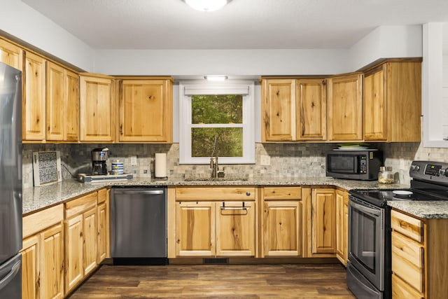 kitchen with tasteful backsplash, dark wood-type flooring, light stone countertops, stainless steel appliances, and a sink