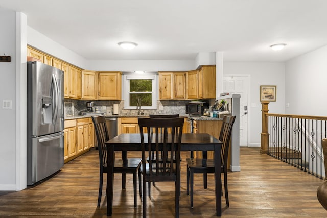 kitchen with sink, appliances with stainless steel finishes, backsplash, dark hardwood / wood-style floors, and stone countertops