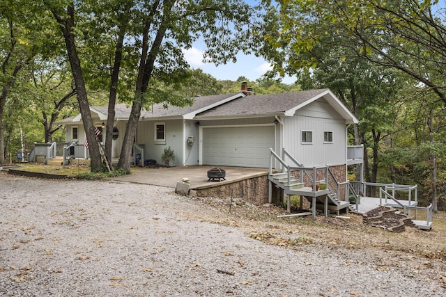 view of front facade with an attached garage, a chimney, driveway, and a shingled roof