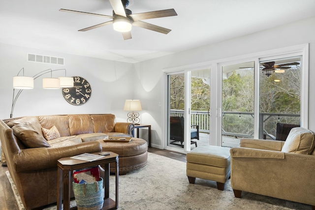 living area featuring baseboards, wood finished floors, visible vents, and ceiling fan