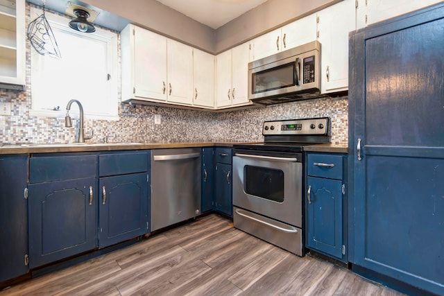 kitchen with blue cabinetry, appliances with stainless steel finishes, dark hardwood / wood-style flooring, and white cabinetry