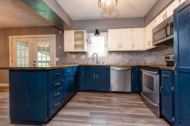 kitchen with appliances with stainless steel finishes, hardwood / wood-style flooring, plenty of natural light, and white cabinets