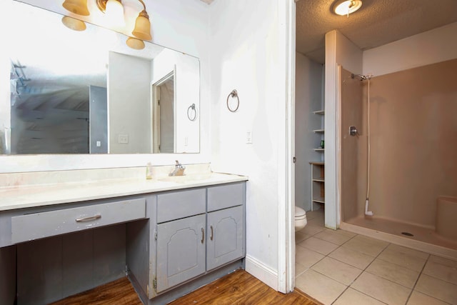 bathroom featuring walk in shower, vanity, toilet, and a textured ceiling