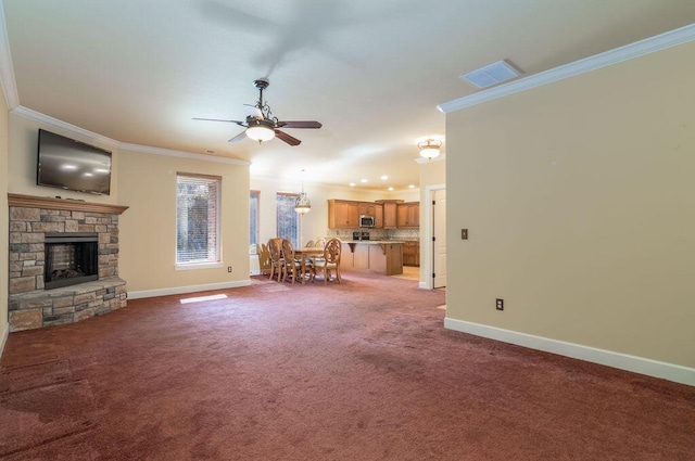 unfurnished living room with crown molding, ceiling fan, a fireplace, and dark carpet