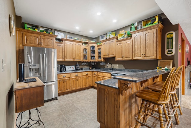 kitchen featuring stainless steel appliances, kitchen peninsula, a kitchen bar, and sink