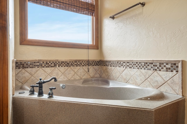 bathroom featuring a relaxing tiled tub and a healthy amount of sunlight