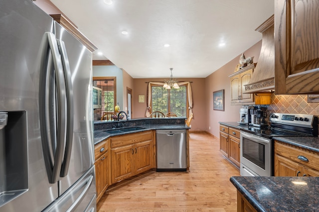 kitchen featuring pendant lighting, sink, light hardwood / wood-style flooring, backsplash, and stainless steel appliances