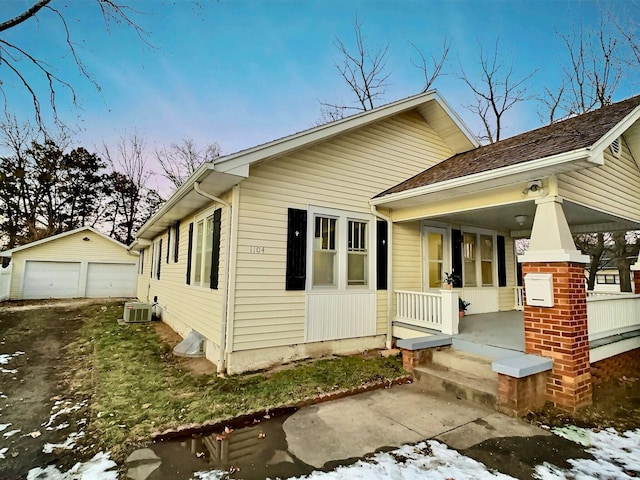 exterior space featuring a porch, cooling unit, a garage, and an outdoor structure