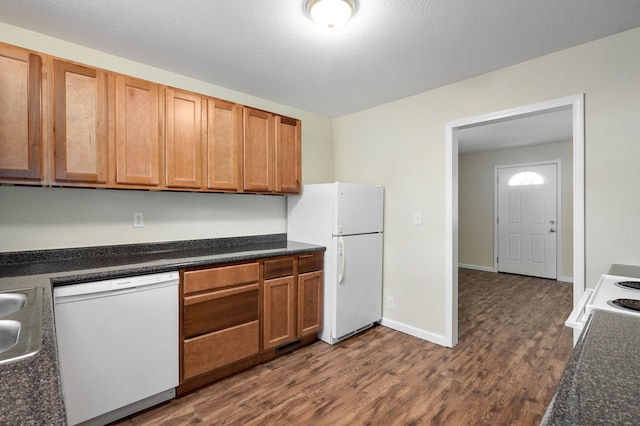 kitchen with a textured ceiling, dark hardwood / wood-style floors, sink, and white appliances