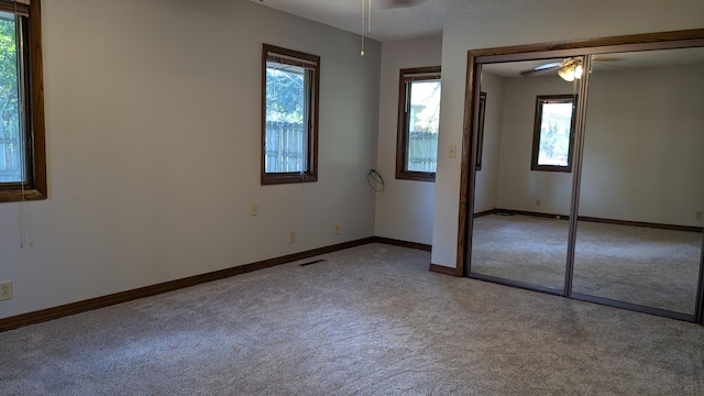 unfurnished bedroom with baseboards, carpet, a closet, and multiple windows