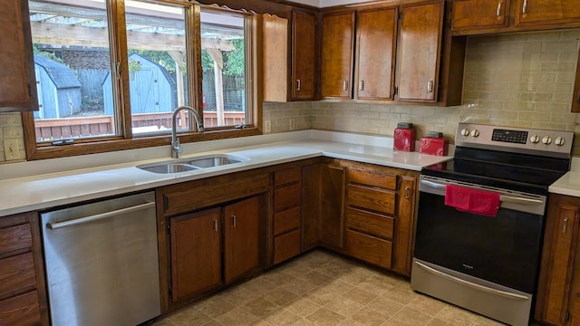 kitchen with appliances with stainless steel finishes, tasteful backsplash, a sink, and light countertops