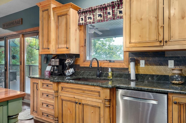 kitchen featuring dishwasher, dark stone counters, sink, and a healthy amount of sunlight