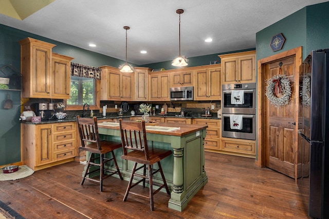 kitchen featuring a center island, dark hardwood / wood-style floors, stainless steel appliances, butcher block counters, and pendant lighting