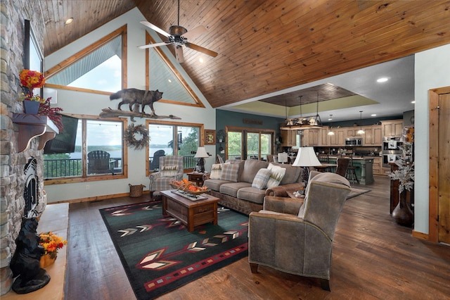 living room featuring ceiling fan, a stone fireplace, dark hardwood / wood-style floors, and high vaulted ceiling