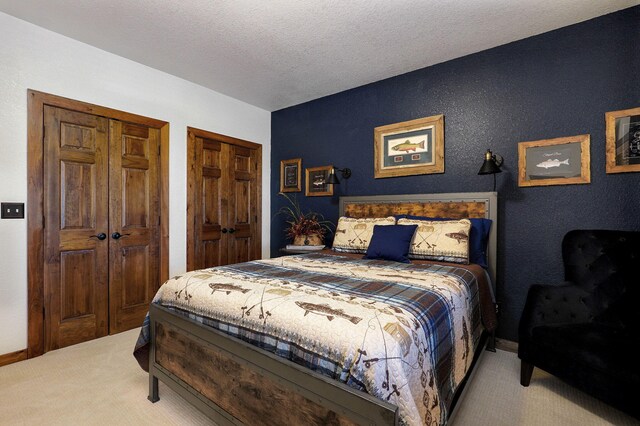 carpeted bedroom with multiple closets and a textured ceiling