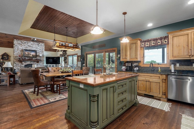 kitchen featuring dishwasher, dark wood-type flooring, a center island, and a stone fireplace