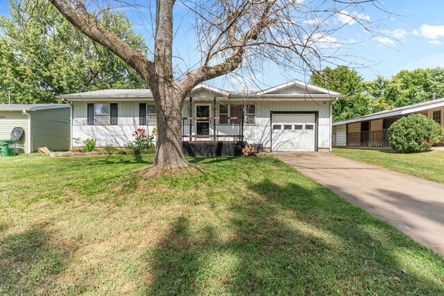 single story home featuring a front yard, a porch, and a garage