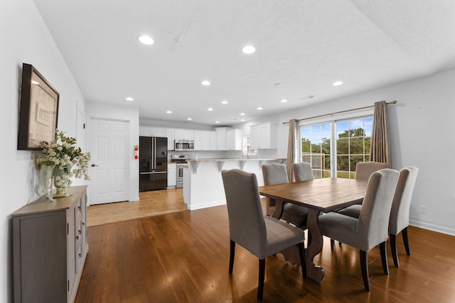 dining space with hardwood / wood-style flooring and a textured ceiling