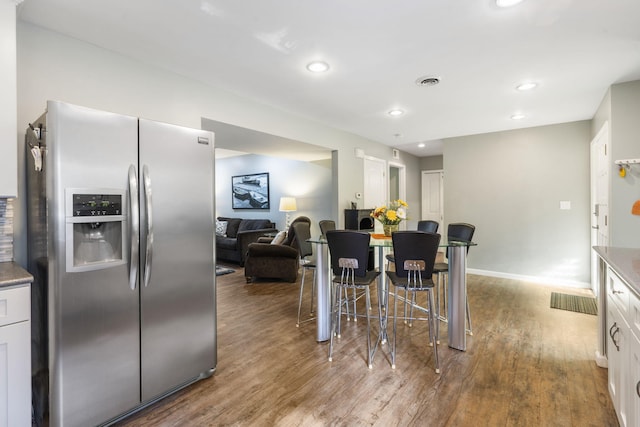 kitchen featuring white cabinetry, wood-type flooring, and stainless steel fridge