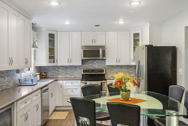 kitchen featuring white cabinets, decorative light fixtures, and stainless steel appliances