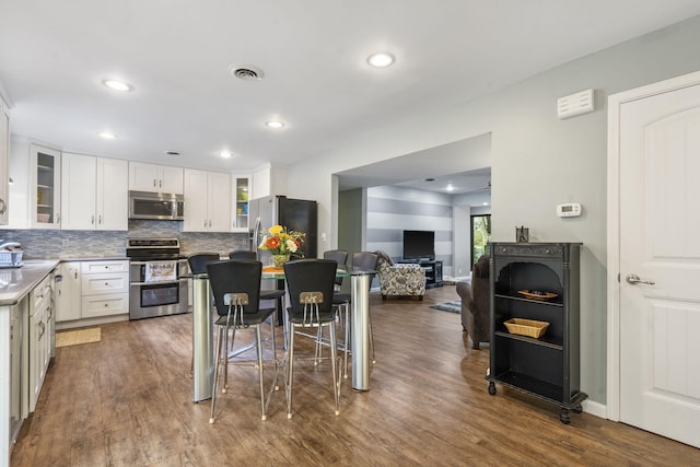 kitchen with stainless steel appliances, dark hardwood / wood-style floors, and white cabinets