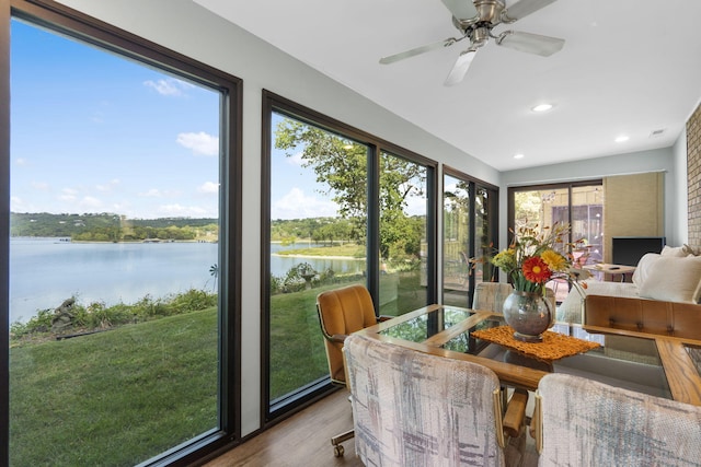 sunroom / solarium with a water view and ceiling fan