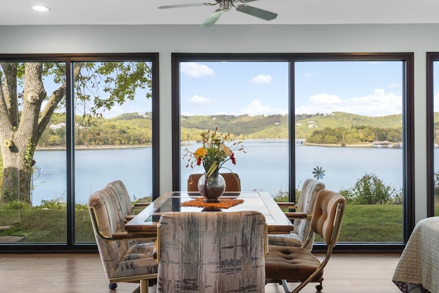 sunroom / solarium featuring a water view, ceiling fan, and a wealth of natural light