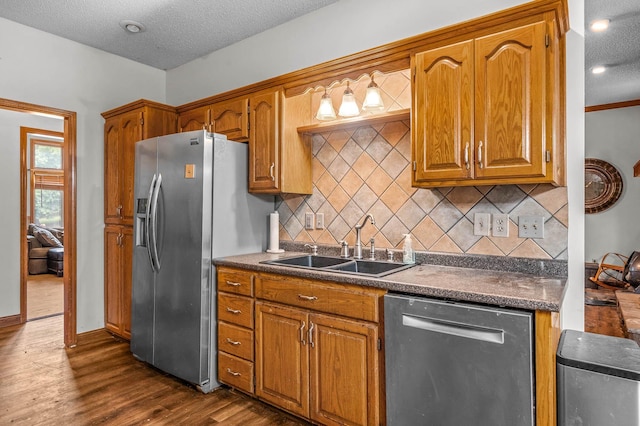 kitchen with dark wood-type flooring, a textured ceiling, sink, backsplash, and appliances with stainless steel finishes