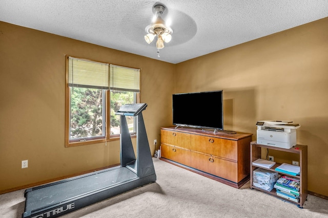 workout area featuring ceiling fan, a textured ceiling, and light carpet