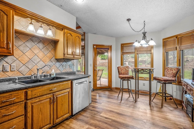 kitchen with stainless steel dishwasher, a textured ceiling, light hardwood / wood-style floors, and plenty of natural light