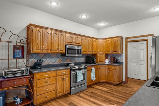 kitchen featuring decorative backsplash, stainless steel appliances, and light hardwood / wood-style flooring