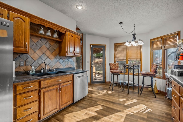 kitchen featuring appliances with stainless steel finishes, backsplash, hanging light fixtures, a notable chandelier, and dark wood-type flooring