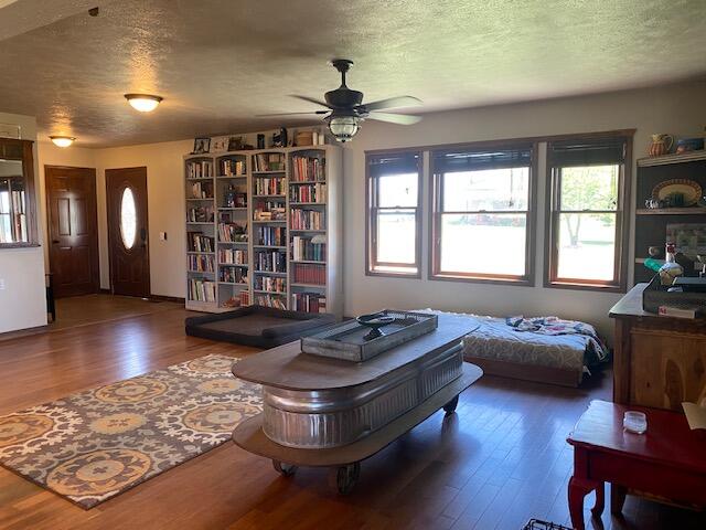 living room featuring dark hardwood / wood-style flooring, a textured ceiling, and ceiling fan