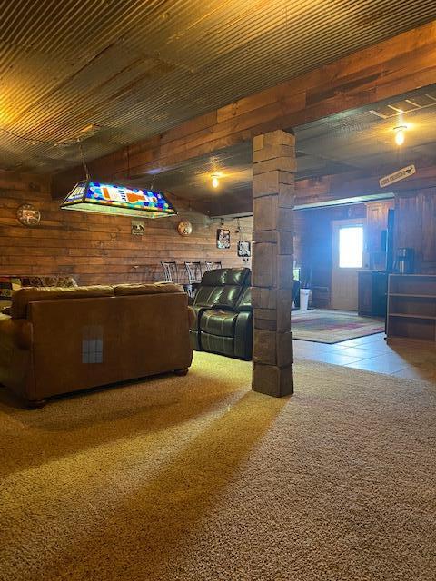 unfurnished living room featuring wooden walls and carpet floors