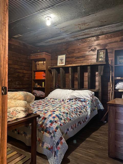 bedroom featuring wood walls and dark hardwood / wood-style flooring