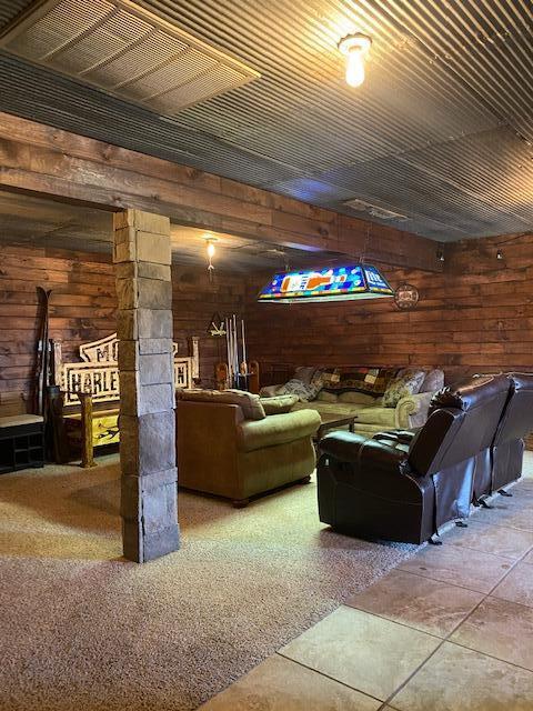 living room with wood walls, ornate columns, and carpet floors