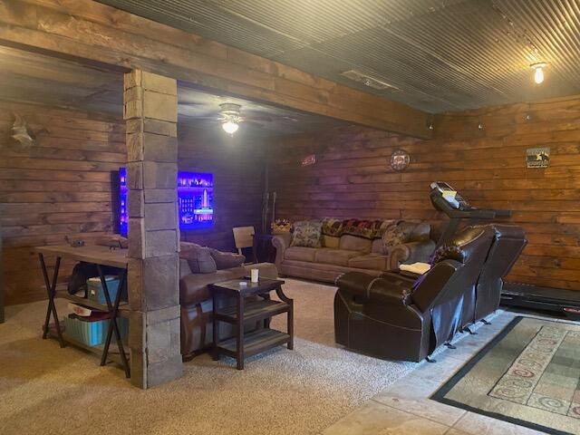 living room with wooden walls, ceiling fan, and carpet