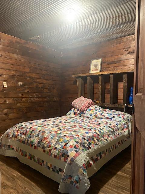 bedroom with wooden walls and dark hardwood / wood-style floors