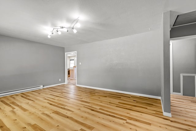 spare room with track lighting, a baseboard heating unit, light hardwood / wood-style floors, and a textured ceiling