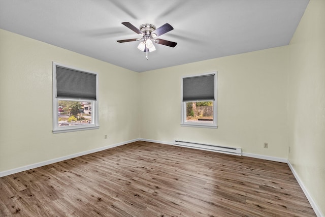 spare room featuring ceiling fan, a baseboard radiator, hardwood / wood-style flooring, and a healthy amount of sunlight