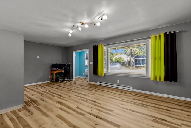 unfurnished room featuring a baseboard radiator, light hardwood / wood-style floors, and a textured ceiling