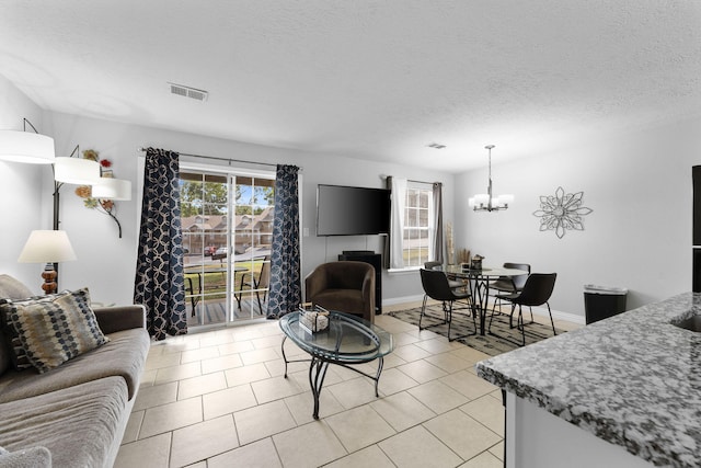 living room featuring light tile patterned flooring, a notable chandelier, and a textured ceiling